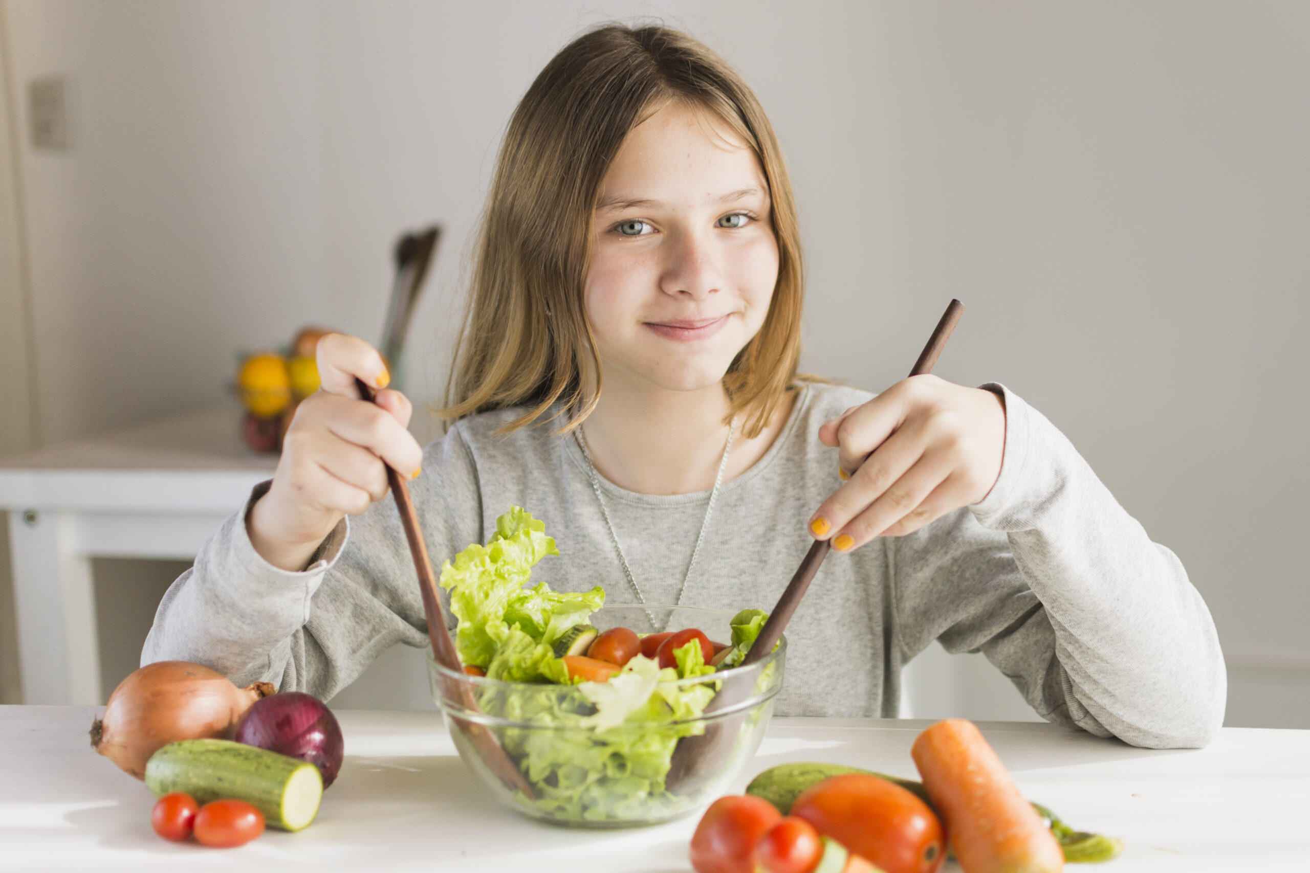 smiling girl making healthy vegetable salad scaled